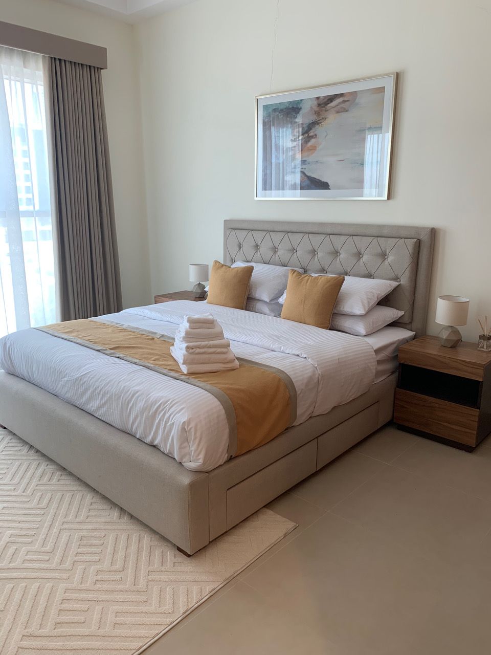 Bedroom with a tall channel-stitched headboard and layered curtains
